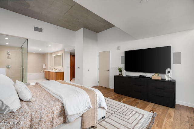 bedroom with ensuite bathroom and light hardwood / wood-style flooring