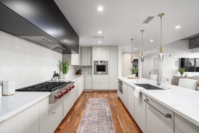 kitchen with stainless steel appliances, white cabinetry, custom exhaust hood, and sink