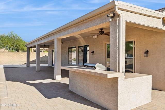 view of patio featuring exterior kitchen, a grill, and ceiling fan