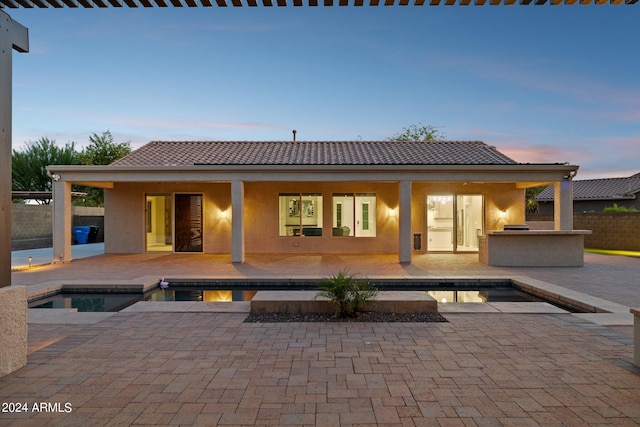 back house at dusk with area for grilling, a patio area, and a swimming pool with hot tub