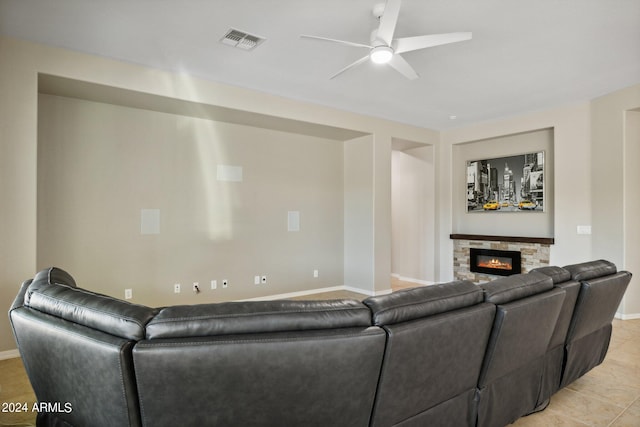 tiled living room with ceiling fan and a fireplace