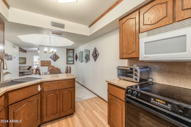 kitchen with an inviting chandelier, a textured ceiling, black range with electric stovetop, pendant lighting, and light hardwood / wood-style flooring