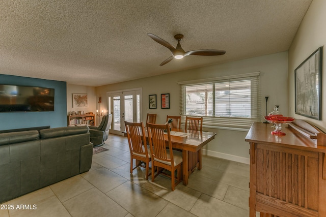 tiled dining space with a ceiling fan, french doors, a textured ceiling, and baseboards