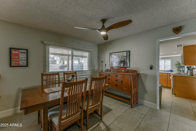 dining area with light tile patterned floors, visible vents, a ceiling fan, a textured ceiling, and baseboards
