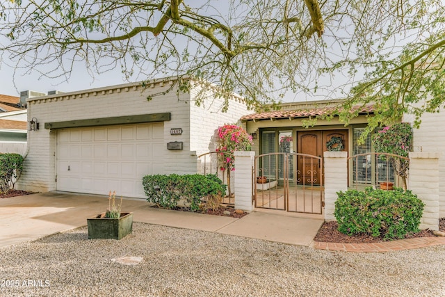 view of front of house featuring a garage, a tile roof, a gate, and central AC