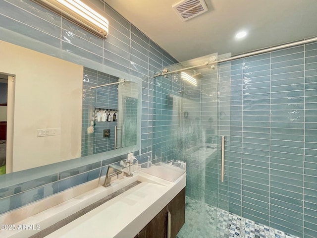 bathroom with tile walls, tiled shower, visible vents, and vanity