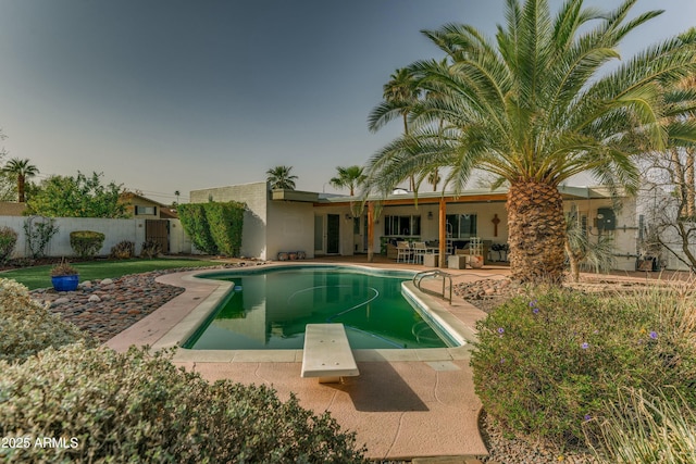 view of swimming pool with a diving board, a patio area, fence, and a fenced in pool