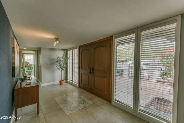 entryway with light tile patterned flooring and baseboards