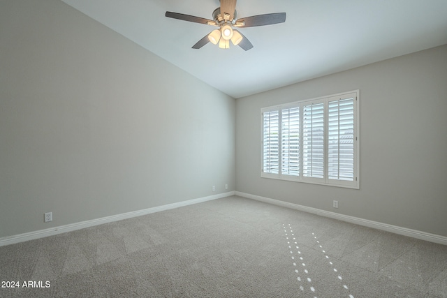 spare room featuring ceiling fan, light carpet, and vaulted ceiling