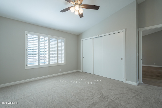 unfurnished bedroom with ceiling fan, a closet, light carpet, and lofted ceiling