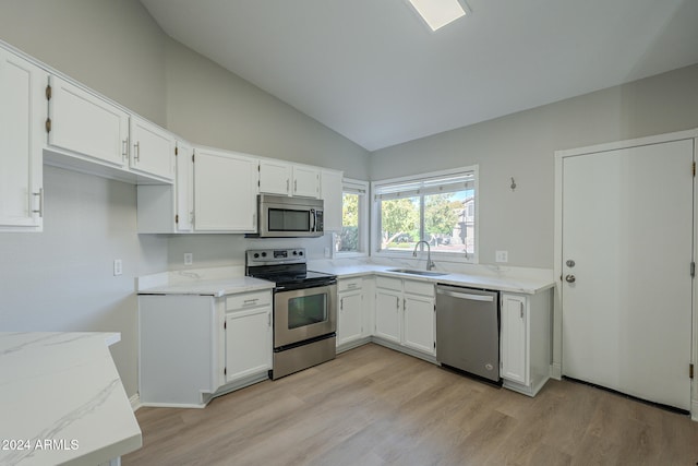 kitchen with light wood-type flooring, white cabinetry, stainless steel appliances, and vaulted ceiling