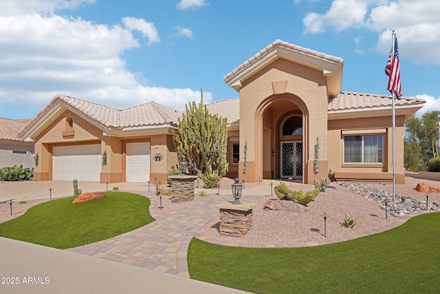 mediterranean / spanish house with an attached garage, driveway, a tiled roof, and stucco siding