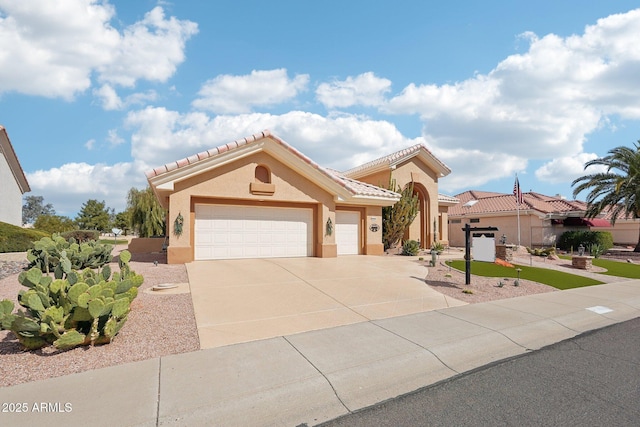 mediterranean / spanish house featuring an attached garage, a tile roof, concrete driveway, and stucco siding