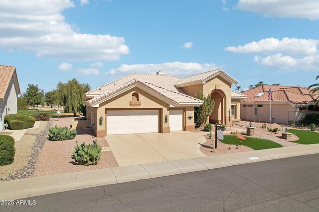 mediterranean / spanish house featuring an attached garage, a tile roof, concrete driveway, and stucco siding