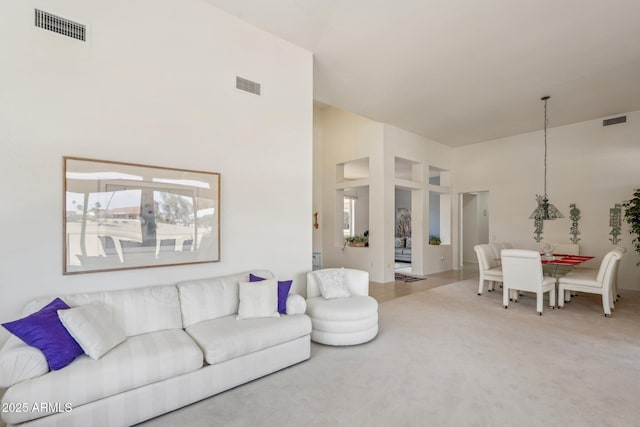 carpeted living area with a high ceiling and visible vents