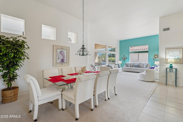 dining room featuring a high ceiling, visible vents, and light tile patterned flooring