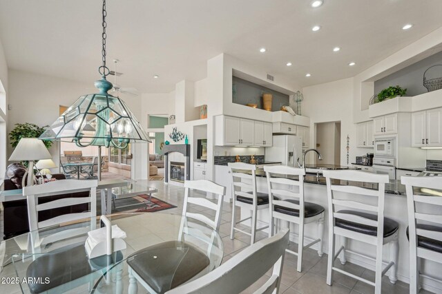 dining space with recessed lighting, light tile patterned flooring, a fireplace, and a high ceiling