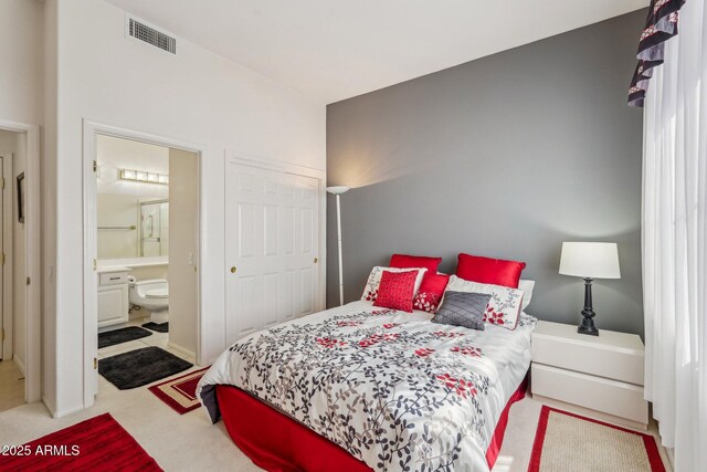 carpeted bedroom with visible vents and ensuite bathroom