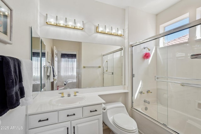 full bath featuring toilet, vanity, bath / shower combo with glass door, and ensuite bathroom