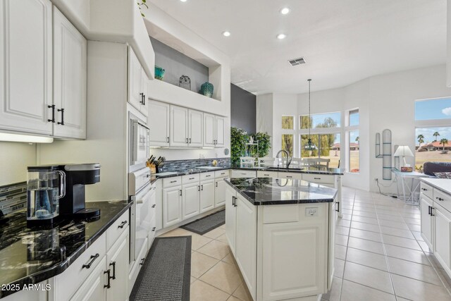 kitchen with light tile patterned floors, white appliances, a peninsula, white cabinetry, and a sink