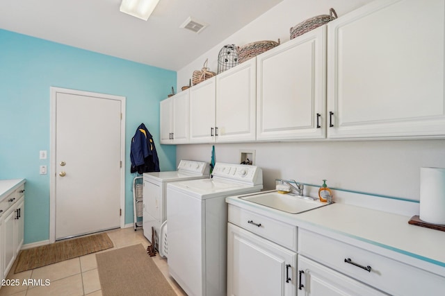 clothes washing area with washing machine and clothes dryer, light tile patterned floors, cabinet space, visible vents, and a sink