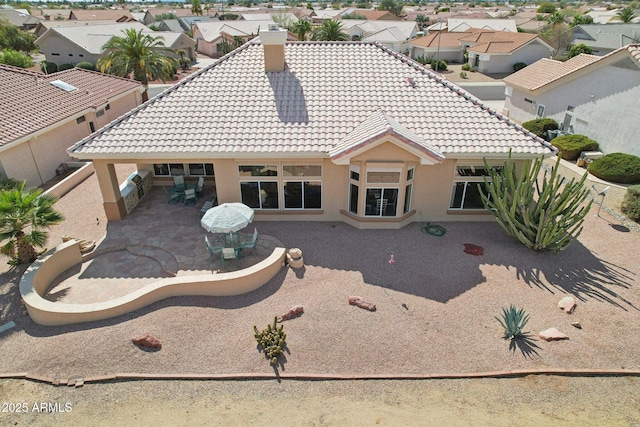 back of house featuring a patio area, a tile roof, and stucco siding