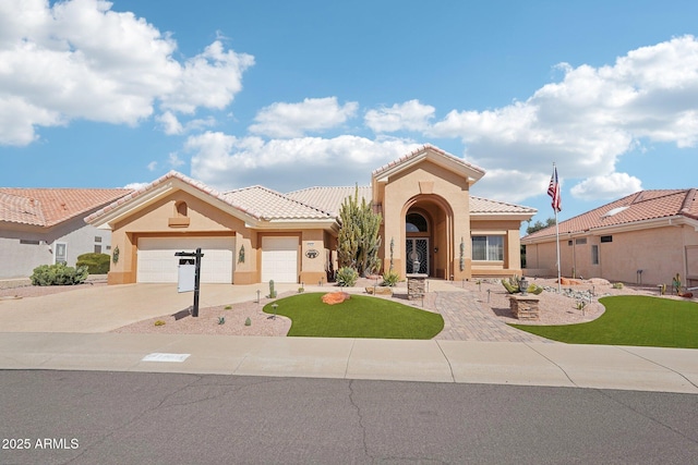 mediterranean / spanish house featuring a tile roof, stucco siding, a front yard, a garage, and driveway