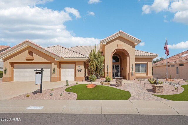 mediterranean / spanish-style house featuring a tile roof, an attached garage, and stucco siding