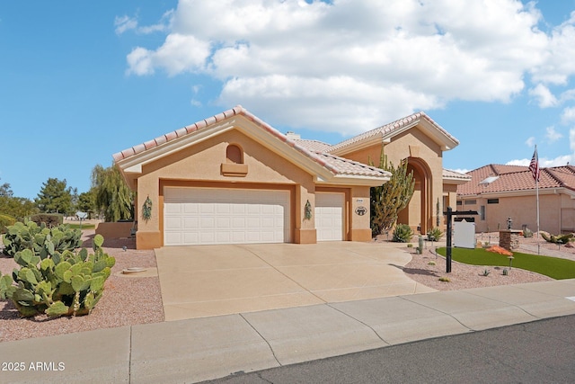 mediterranean / spanish-style home with a garage, a tiled roof, concrete driveway, and stucco siding