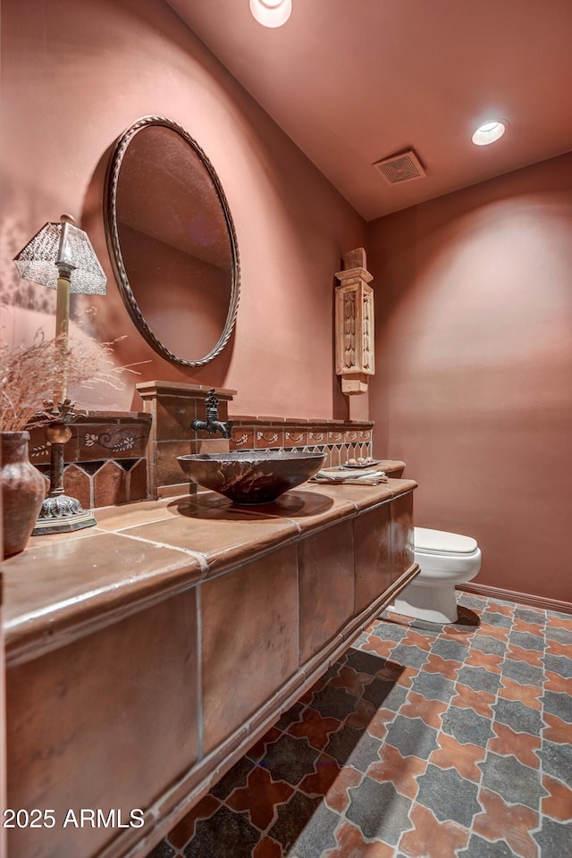 9534 E Monument Dr, Scottsdale, AZ 85262 - bathroom with toilet, vanity, stone finish flooring, and recessed lighting
