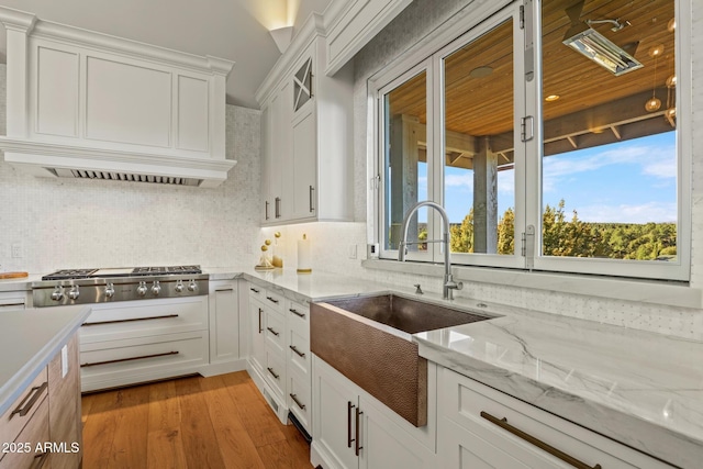 kitchen with light wood-style floors, white cabinetry, stainless steel gas stovetop, and a sink