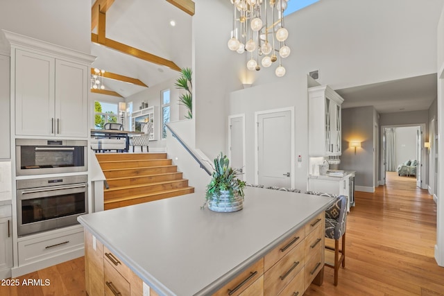 kitchen with light wood-style flooring, white cabinetry, light countertops, and a notable chandelier