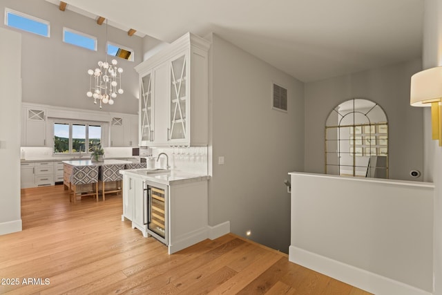 kitchen with beverage cooler, an inviting chandelier, visible vents, and white cabinets