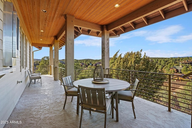 view of patio featuring a balcony and a forest view