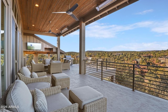 view of patio with an outdoor living space, a wooded view, a balcony, and a ceiling fan