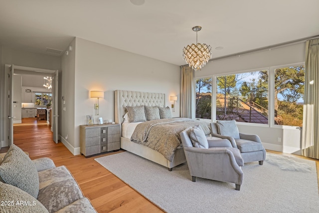 bedroom with an inviting chandelier, light wood-style flooring, and baseboards