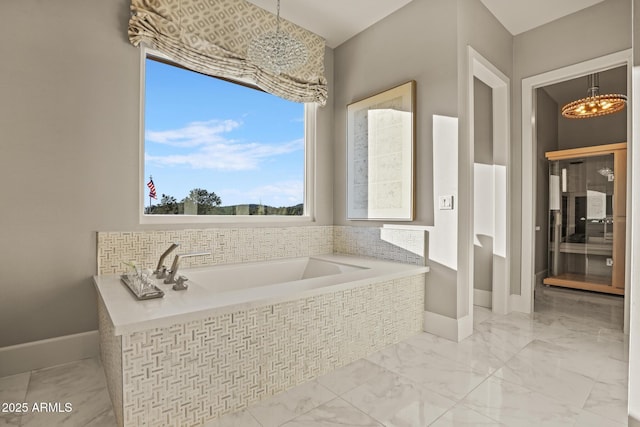 bathroom featuring a chandelier, marble finish floor, a garden tub, and baseboards