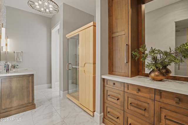 bathroom featuring a stall shower, baseboards, marble finish floor, an inviting chandelier, and vanity