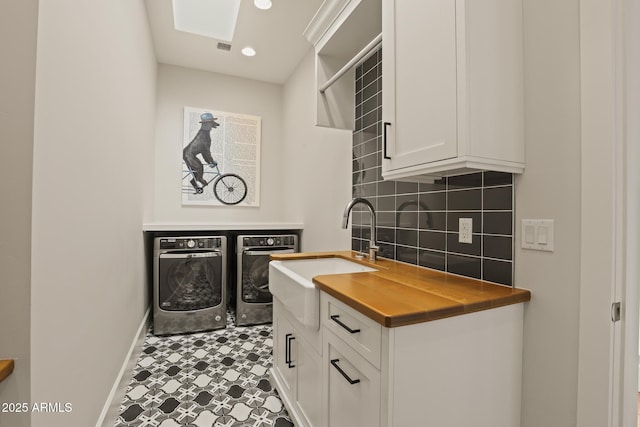 kitchen with tasteful backsplash, butcher block countertops, independent washer and dryer, white cabinetry, and a sink