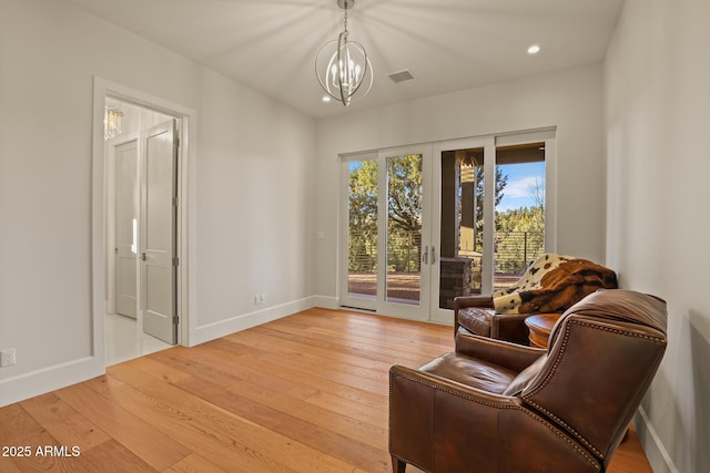 sitting room with a chandelier, baseboards, visible vents, and light wood finished floors