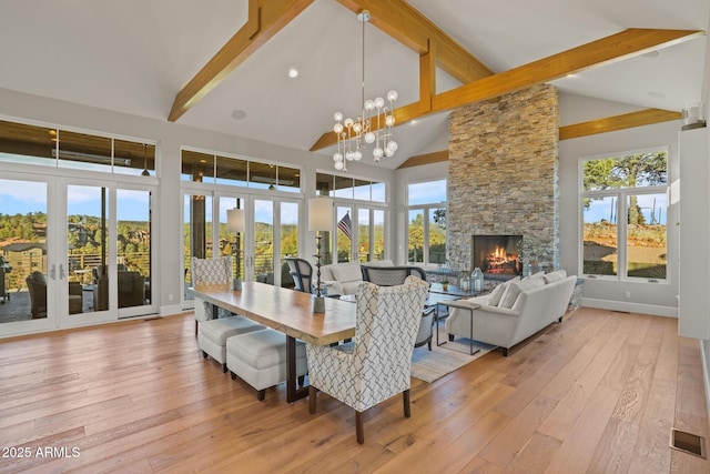 dining room with light wood-style floors, visible vents, beam ceiling, and a stone fireplace