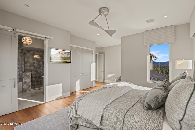 bedroom with a barn door, recessed lighting, a ceiling fan, a closet, and light wood-type flooring