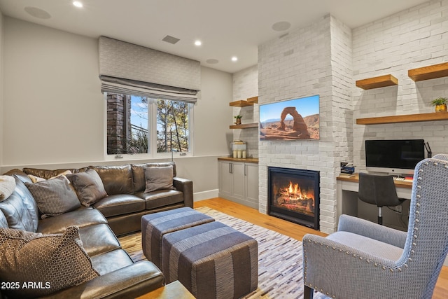 living room with recessed lighting, a fireplace, visible vents, baseboards, and light wood-type flooring