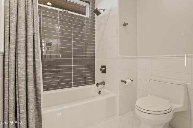 full bathroom featuring toilet, wainscoting, shower / bath combination with curtain, and tile walls