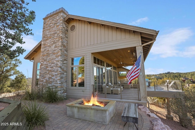 back of property with a ceiling fan, an outdoor fire pit, a patio area, and a deck