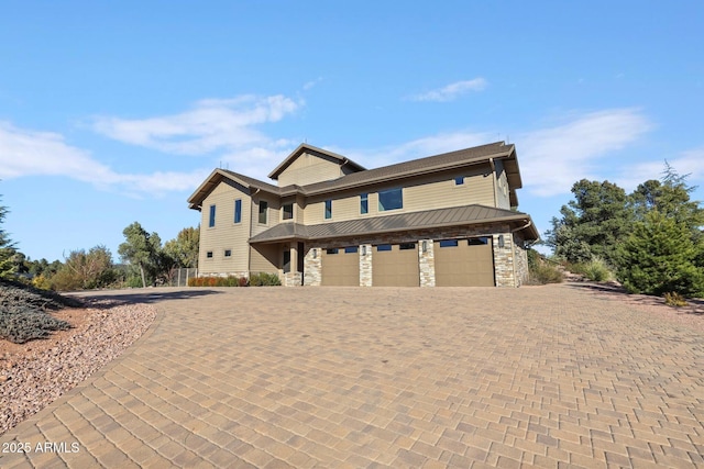 view of front of home featuring a garage, stone siding, and decorative driveway