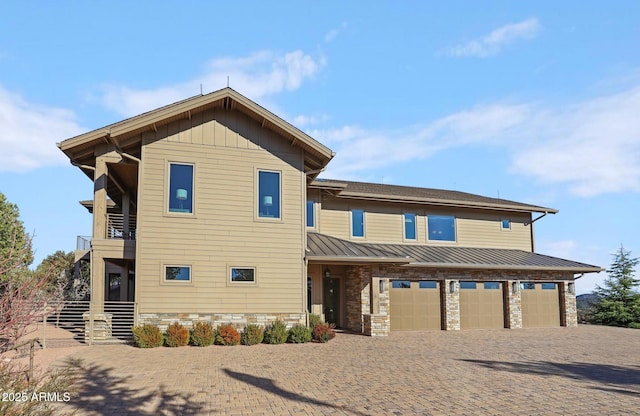 view of front of property featuring a balcony, an attached garage, a standing seam roof, decorative driveway, and board and batten siding