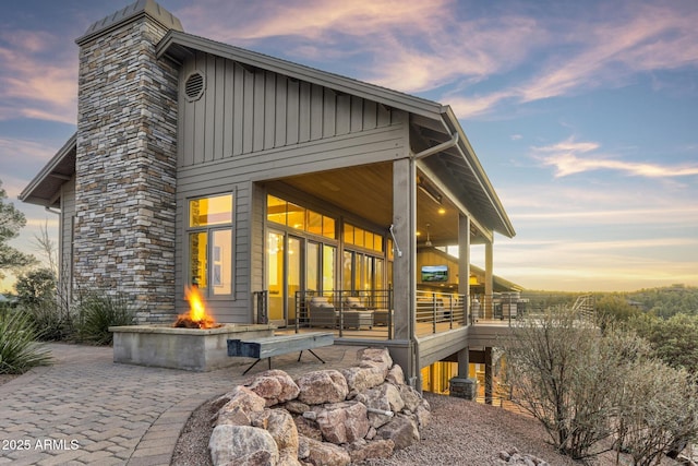 back of house with board and batten siding, an outdoor fire pit, and a patio area