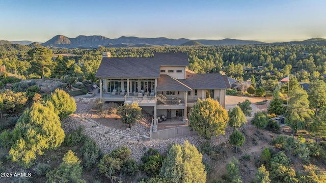 back of property featuring a deck with mountain view, a forest view, and a patio