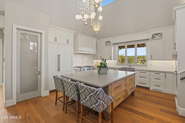 kitchen featuring hardwood / wood-style flooring, a sink, light countertops, a center island, and a kitchen bar